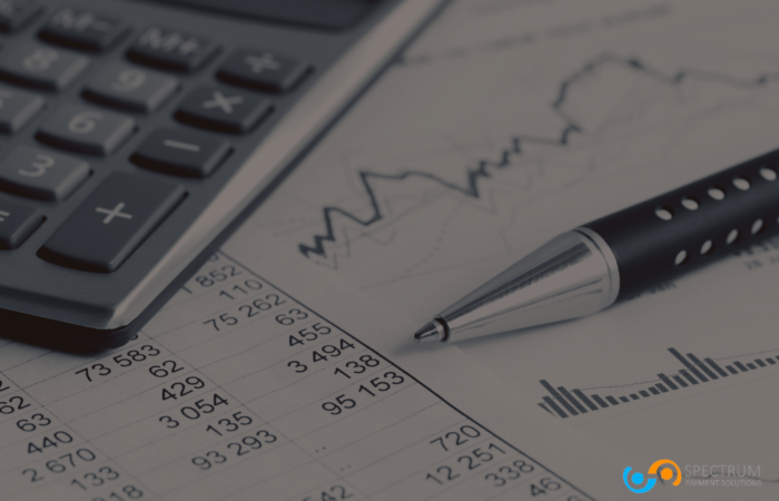 A financial report with a pen and calculator, representing data analysis and financial risk management for high-risk merchant accounts with Spectrum Payment Solutions.
