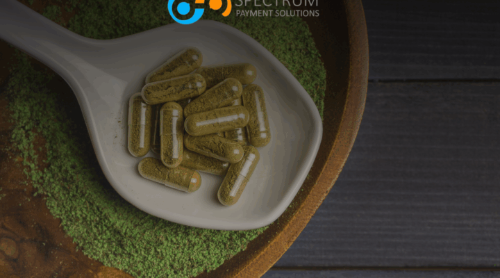 Kratom capsules on white spoon with green kratom powder - Spectrum Payment Solutions merchant processing